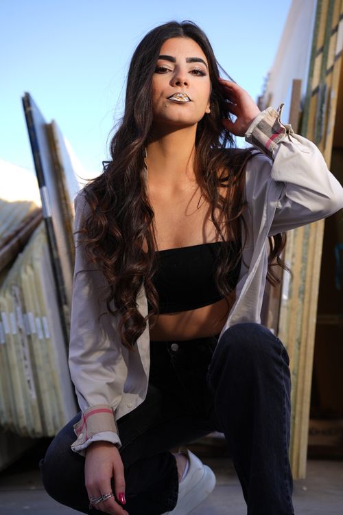 Free Stylish young woman with long hair posing confidently outdoors. Stock Photo