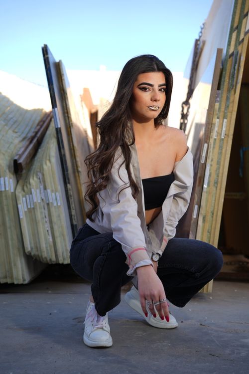 Free Casual and confident young woman posing outdoors amidst urban materials, highlighting a fashionable style. Stock Photo
