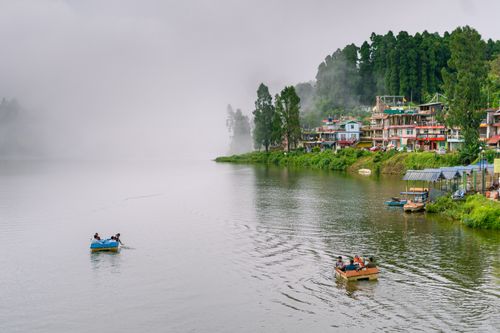 Free Serene boating on misty Mirik Lake with lush greenery and local architecture in West Bengal, India. Stock Photo