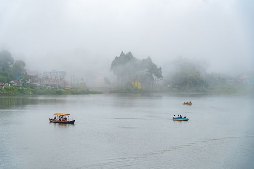 Free Serene view of Mirik Lake in India with boats on a misty morning, capturing tranquility. Stock Photo