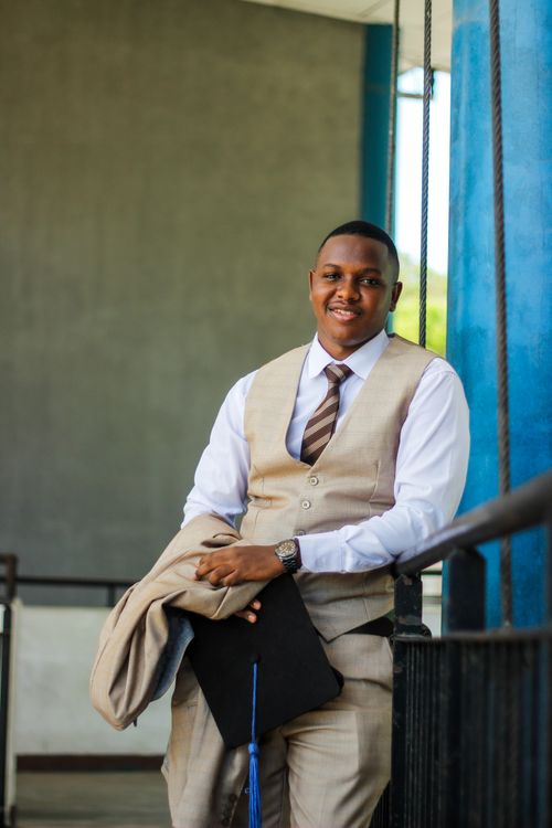 Free Young man in suit holding graduation cap, smiling confidently outdoors. Perfect for education themes. Stock Photo