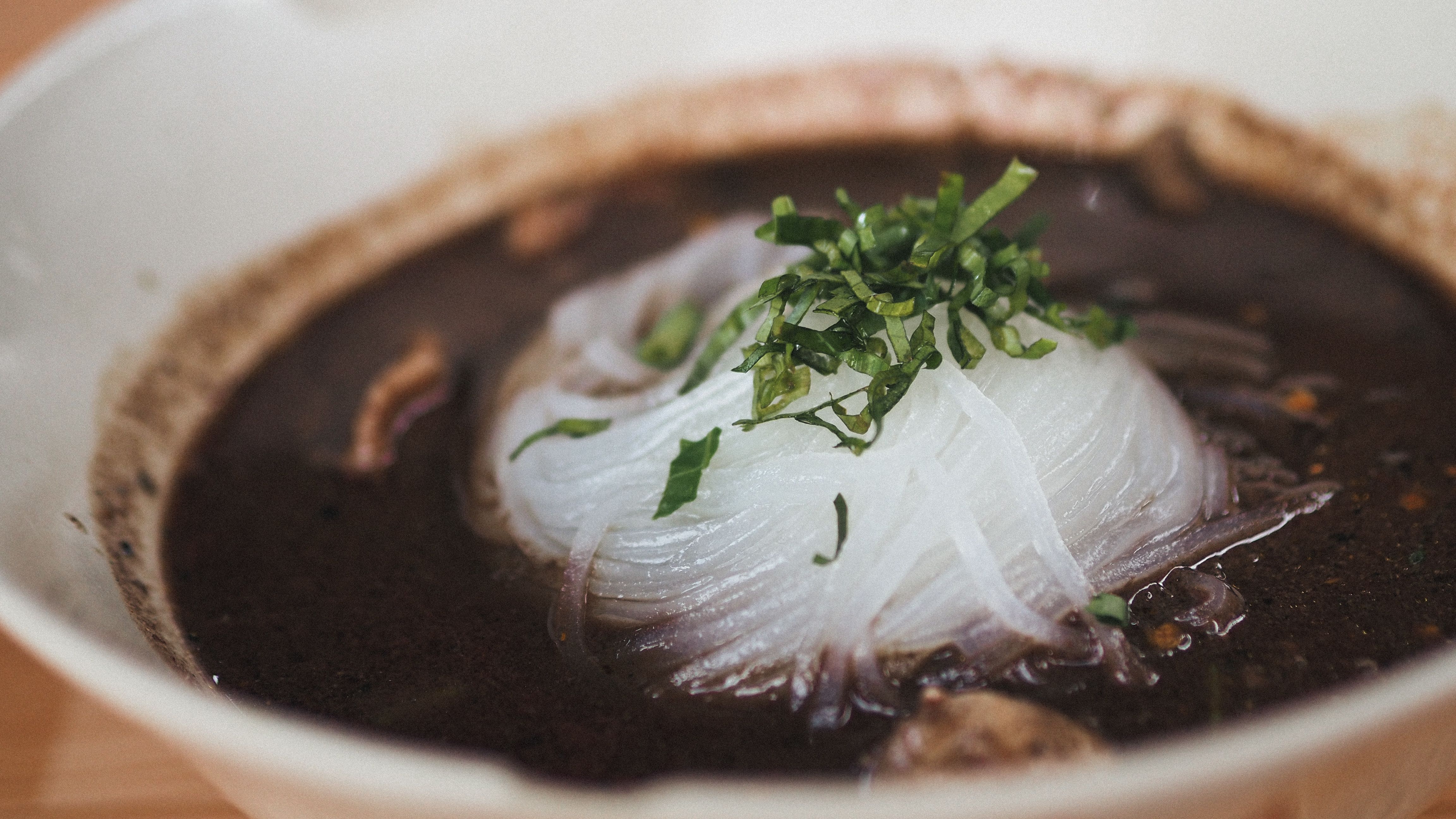 Un tazón de sopa humeante con hierbas frescas