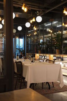 Cozy restaurant interior with elegant lighting and set tables for dining.