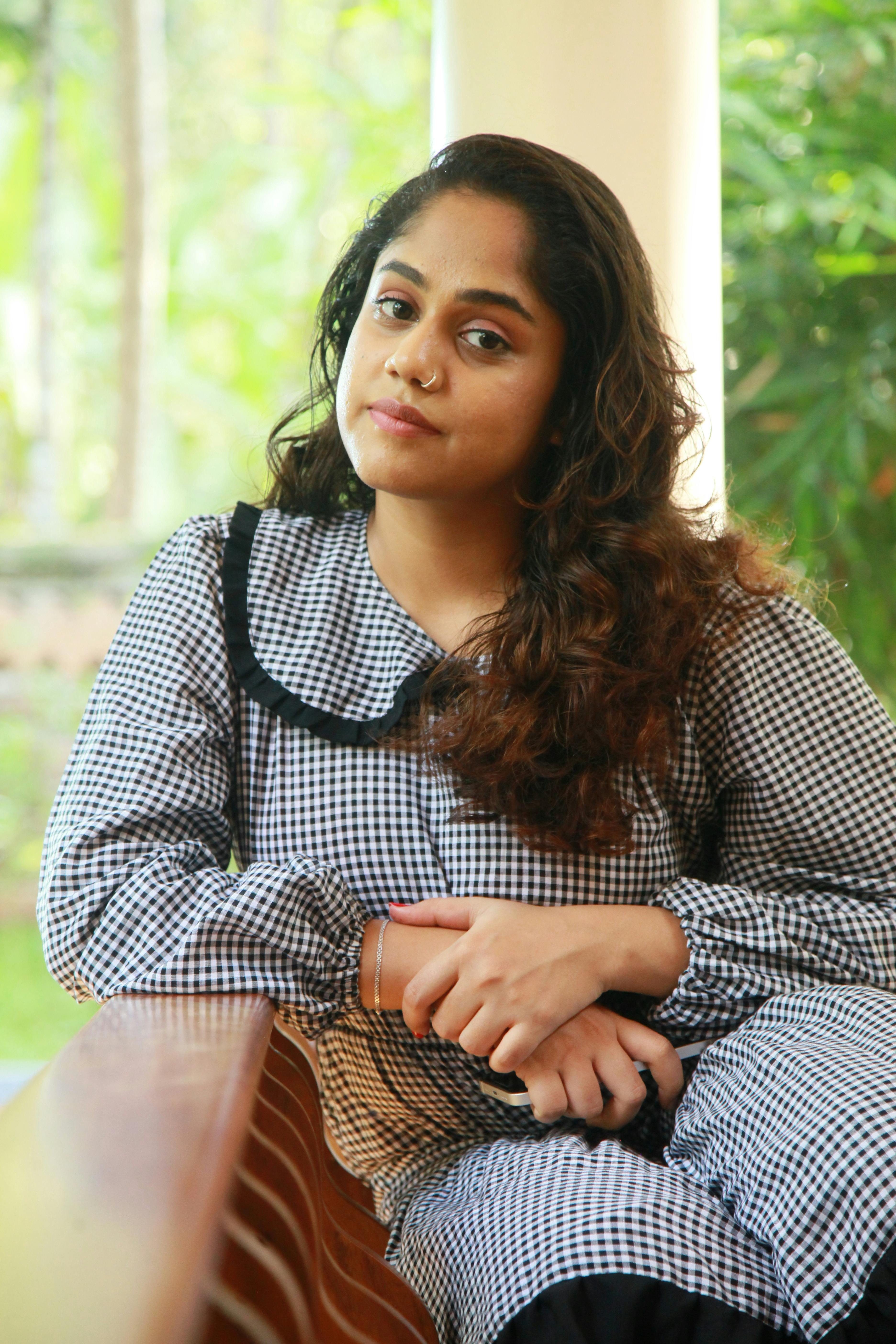 Relaxed portrait of a woman sitting outdoors with soft lighting.