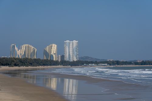 Free Stunning view of modern skyscrapers by a sandy beach under clear blue sky. Stock Photo