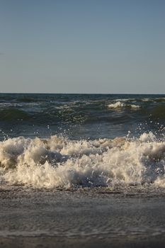 Powerful ocean waves crashing onto the shore on a sunny day with a clear sky.