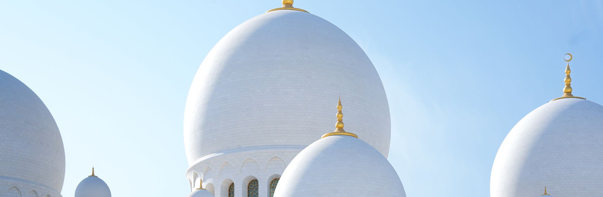 Captivating view of Sheikh Zayed Grand Mosque domes in Abu Dhabi, UAE, under a clear blue sky.