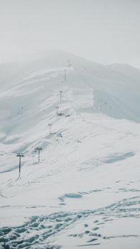 A serene, snow-laden mountain with ski lifts under clear skies.