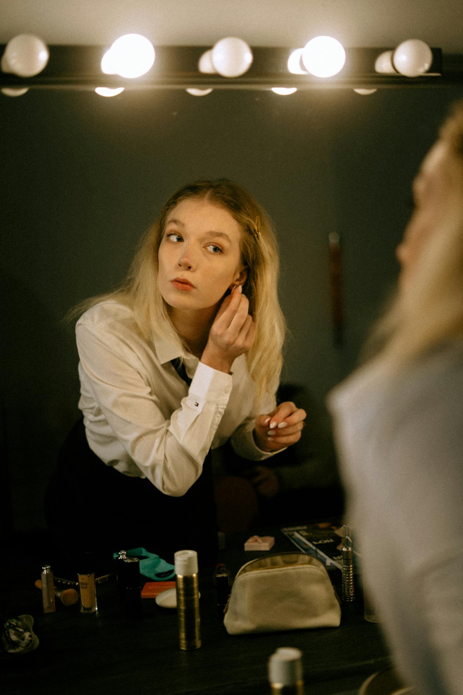 Woman applying makeup in a mirror under indoor lighting