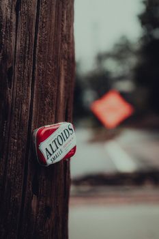 Dramatic urban photo featuring an Altoids tin on a pole with a blurred background.