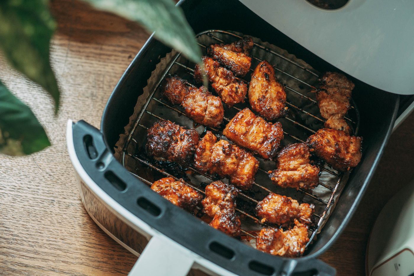 Chicken crisping in a modern air-fryer basket on a wood counter
