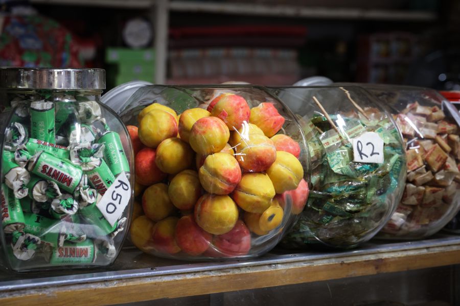 Rows of glass jars filled with brightly coloured sweets on a vintage shop counter