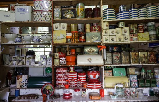 A nostalgic look at a vintage kitchen with assorted tins and crockery on wooden shelves, evoking a classic charm.