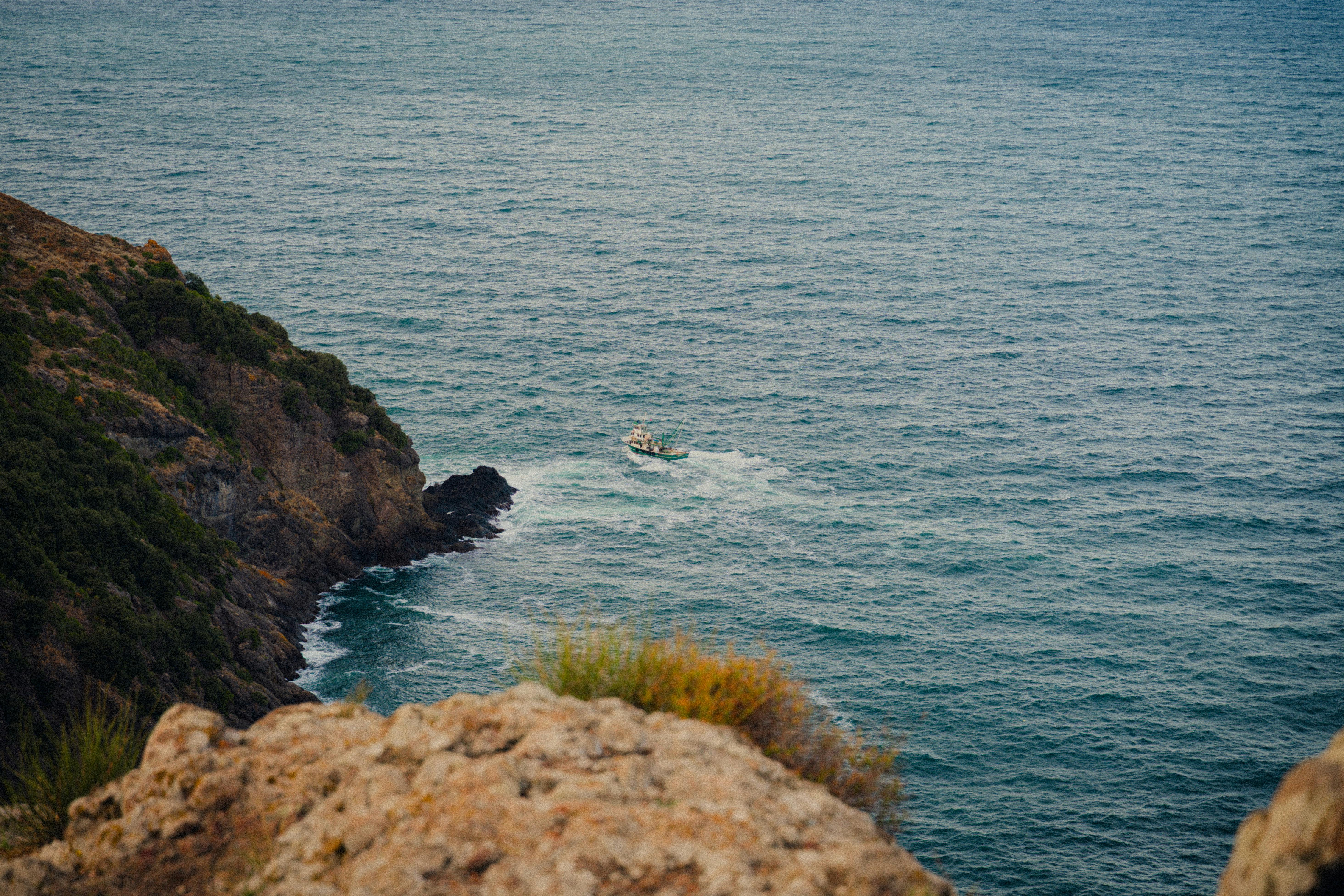 Bezpłatne Samotna łódź płynie po spokojnych wodach w pobliżu skalistego klifu w Synopie w Turcji. Zdjęcie z galerii