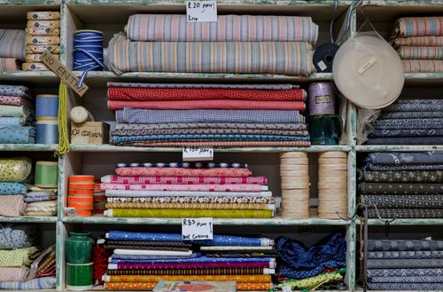 Free Organized shelves with various colorful fabrics, threads, and prices in a textile shop. Stock Photo