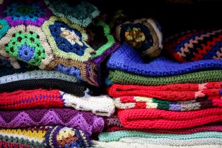 A vibrant stack of vintage crochet blankets showcasing intricate patterns and colorful designs.