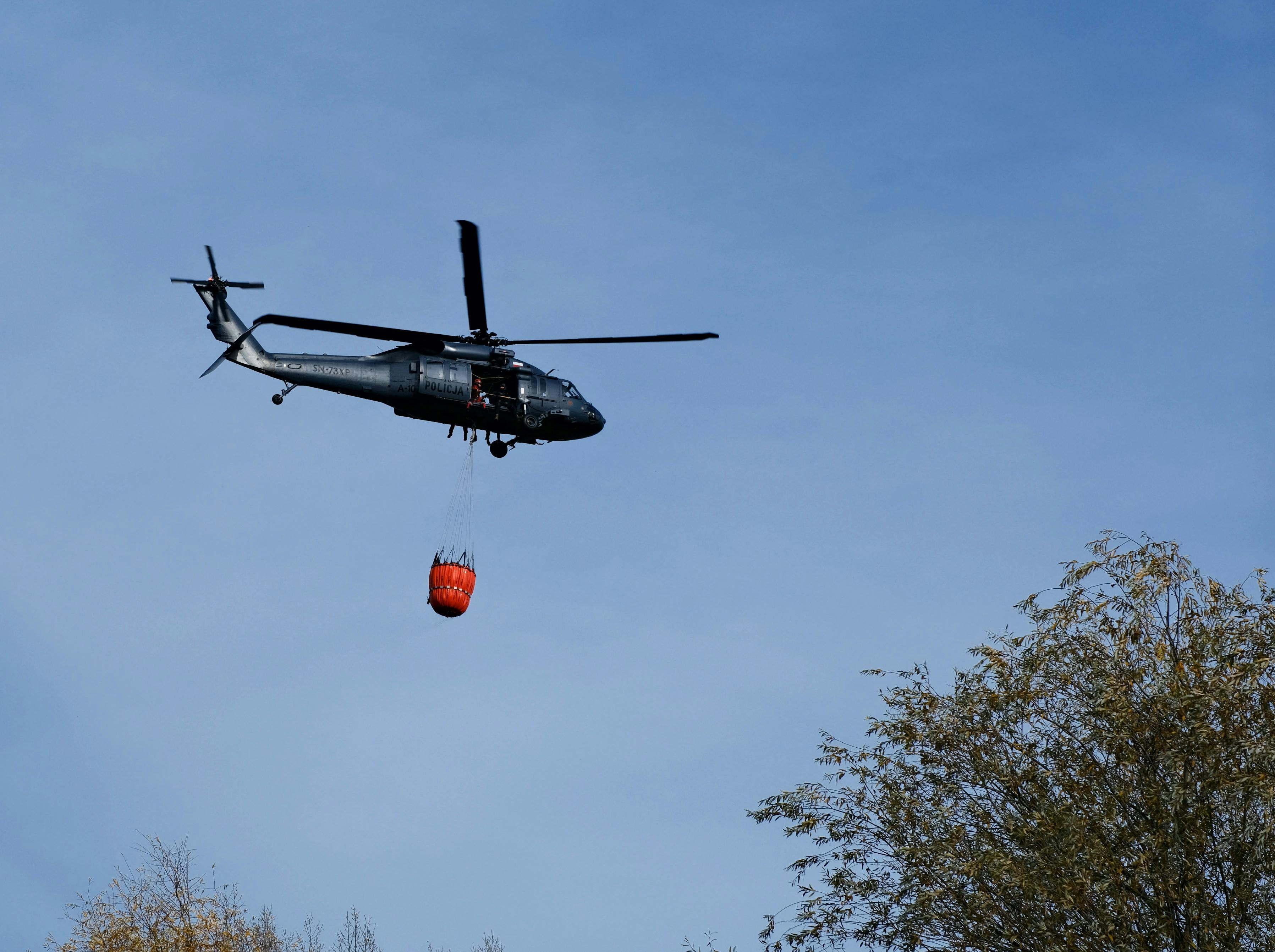 A helicopter conducting a firefighting operation in the clear skies above Wrocław, Poland.