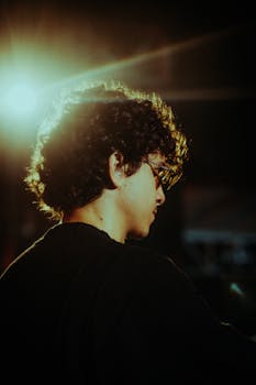 Side profile of a young musician under warm stage lighting, creating an artistic silhouette.