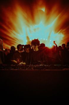 DJ performing in front of a lively crowd with stunning light effects.
