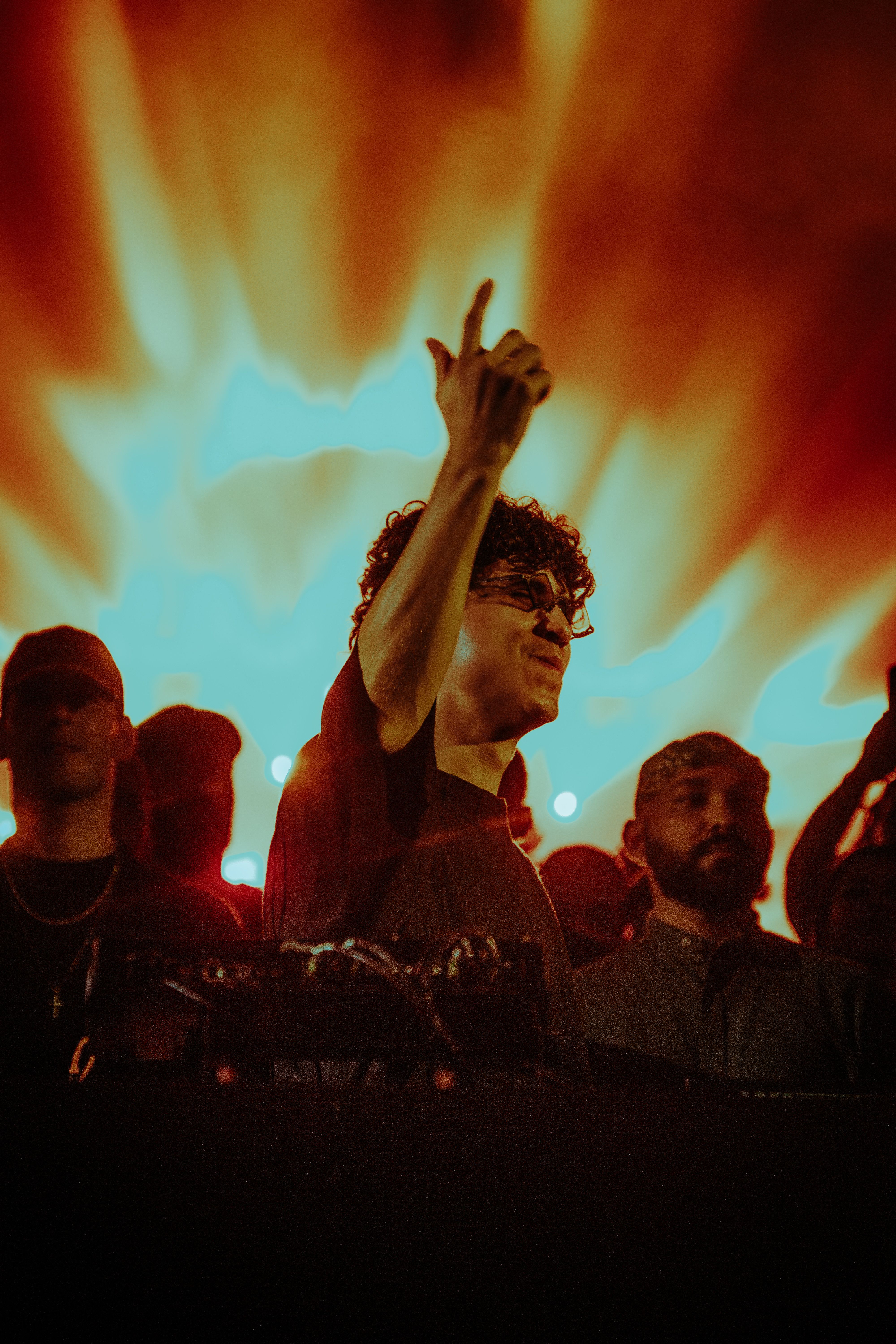 DJ raises the energy with vibrant light display. Captivating concert moment.