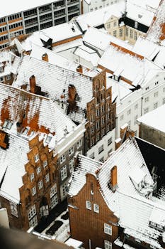 Charming snowy rooftops of historic buildings in a European city captured from above.