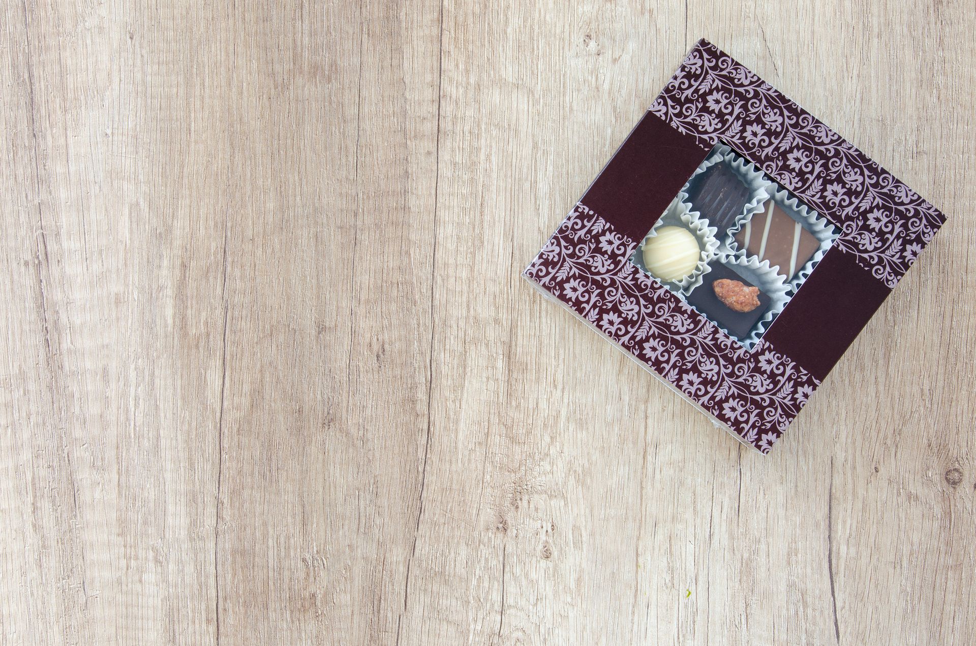 An elegant box of assorted chocolates placed on a rustic wooden table, perfect for a gift.