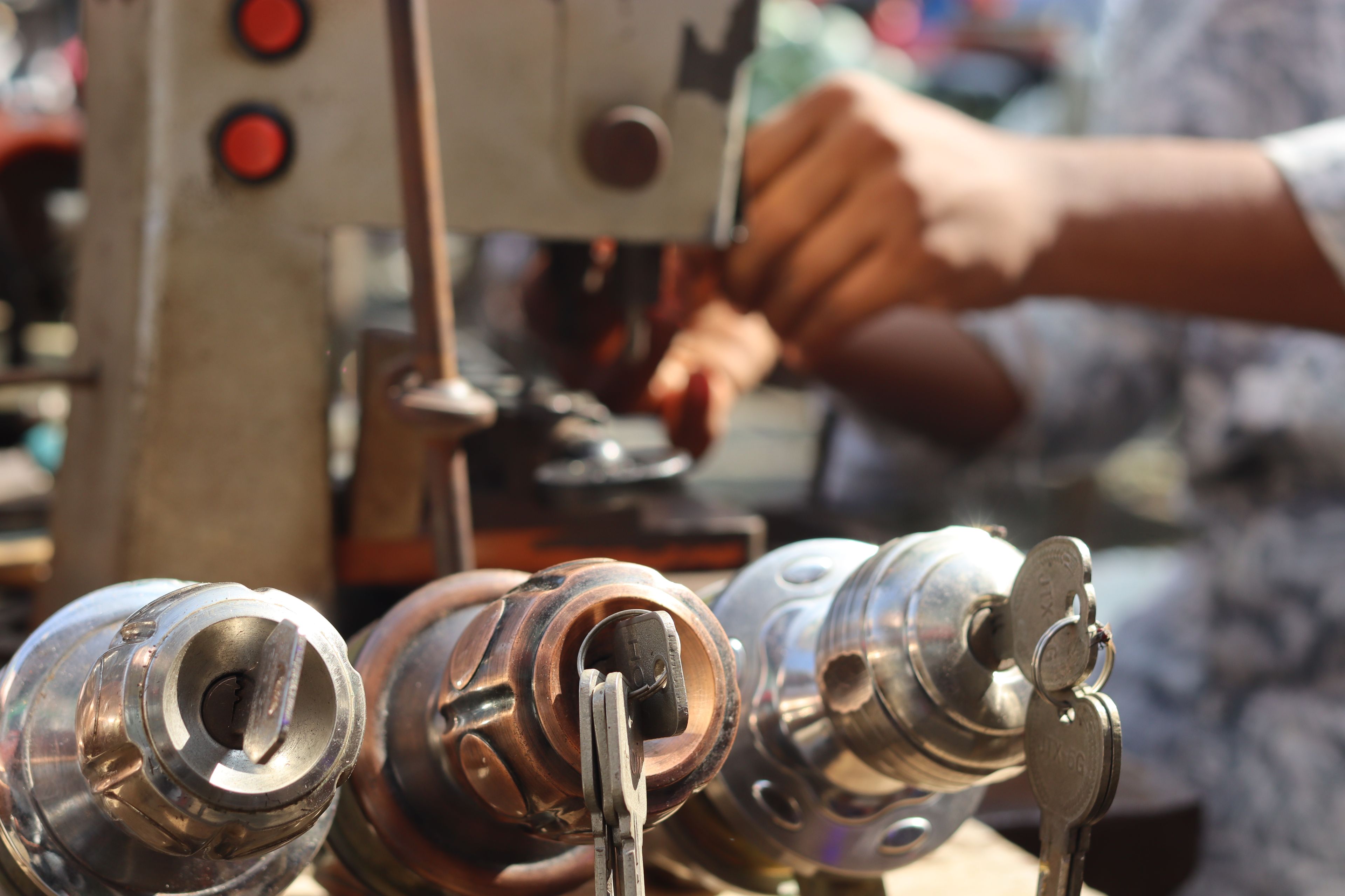 Key being cut on a duplicating machine beside a row of lock cylinders