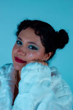 Close-up portrait of a woman with snowflake makeup, wearing a white fur coat.
