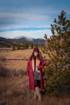 Woman in a red coat stands in a scenic winter landscape in Colorado's Rocky Mountains.
