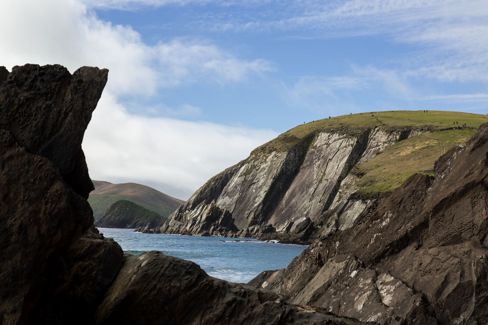 View of the rugged cliffs along Dingle Peninsula, Ireland under a bright blue sky