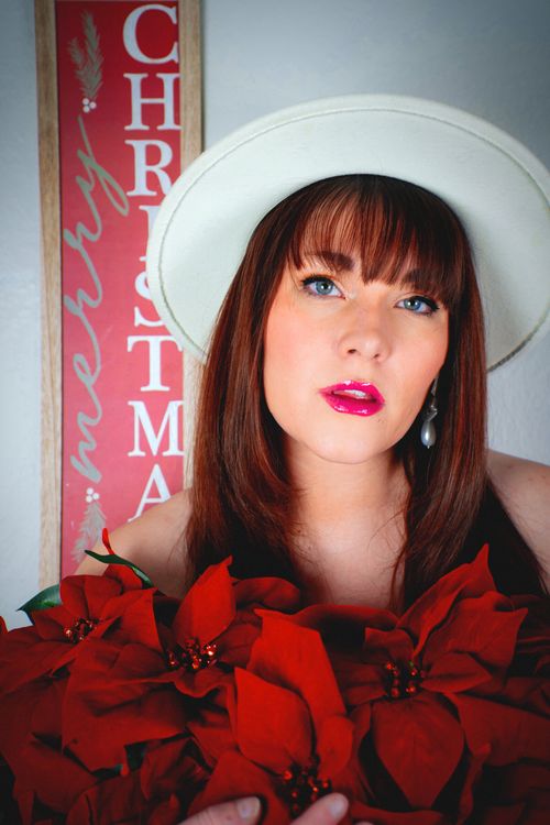 Free Stylish woman in a white hat surrounded by poinsettias, with Christmas theme decor. Stock Photo