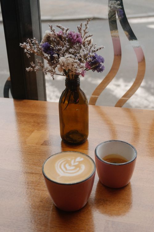 Free Warm coffee table setting with latte art and dried flowers in a cozy café atmosphere. Stock Photo