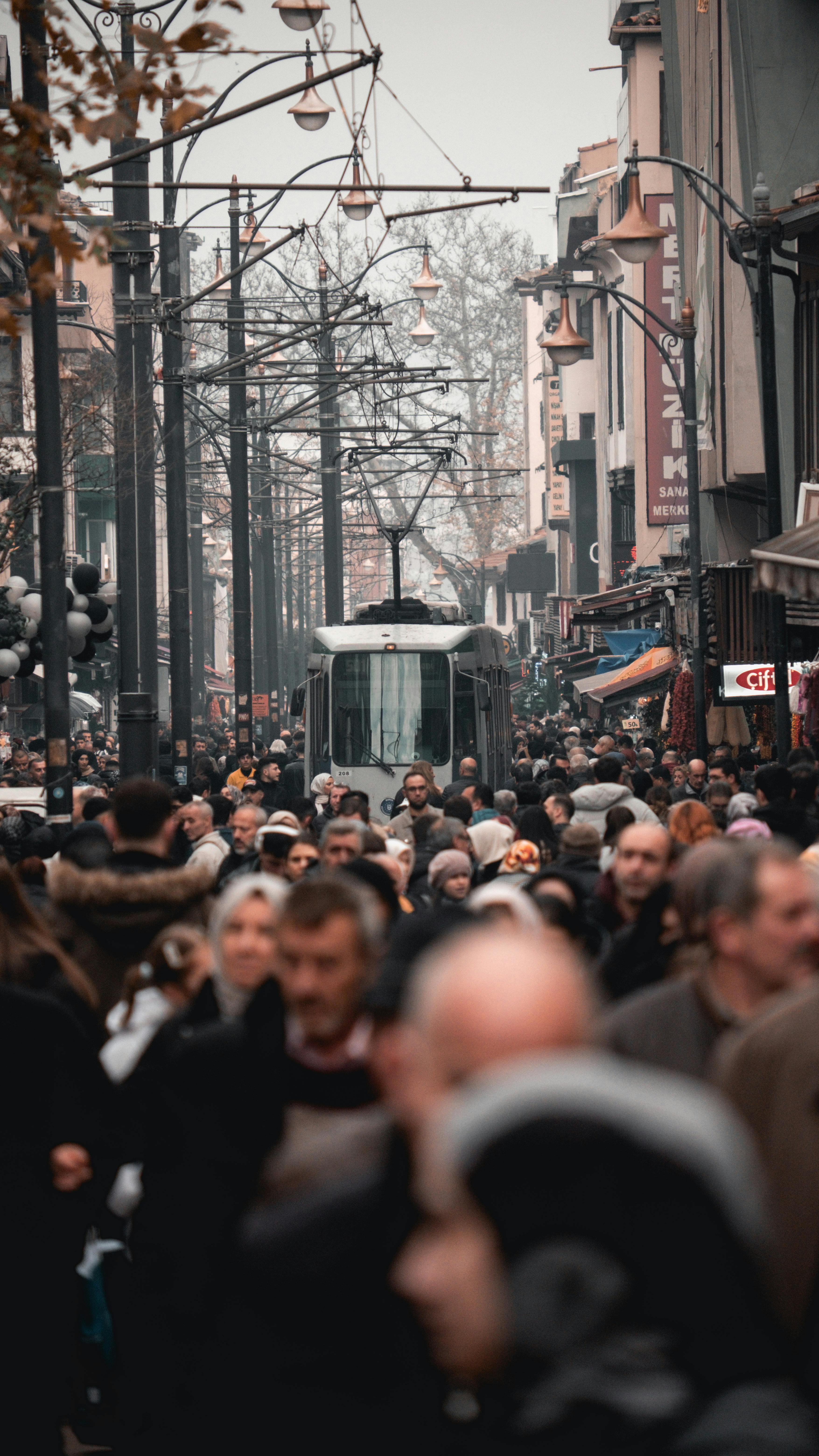Busy city street scene with tram and diverse crowd, creating urban atmosphere.