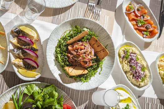 Top-down view of Mediterranean dishes including salads and seafood on an elegant table setting.