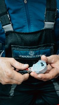 Close-up of a technician working on a small device with precise tools.