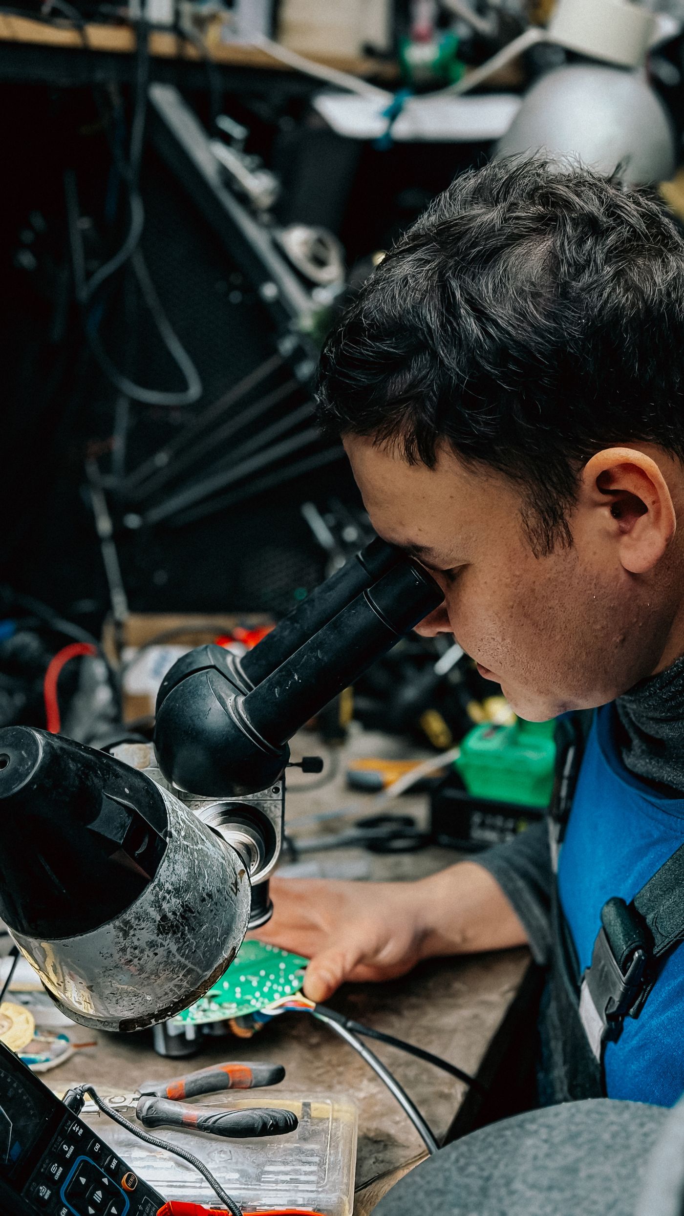 An engineer at a microscope working on a circuit board