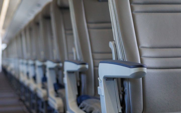 Interior view of an airplane cabin showcasing rows of empty seats, emphasizing travel and aviation themes.
