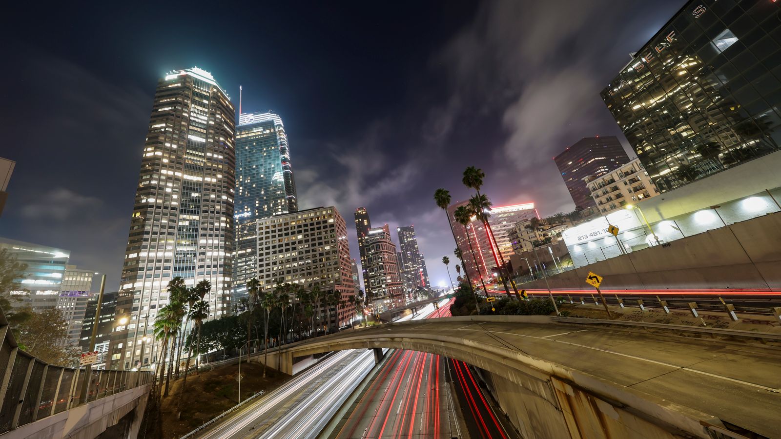 Wide night view of the Los Angeles skyline with glowing skyscrapers and light trails, illustrative photo of the Los Angeles setting of The Further Mis-Adventures of Cliff Booth