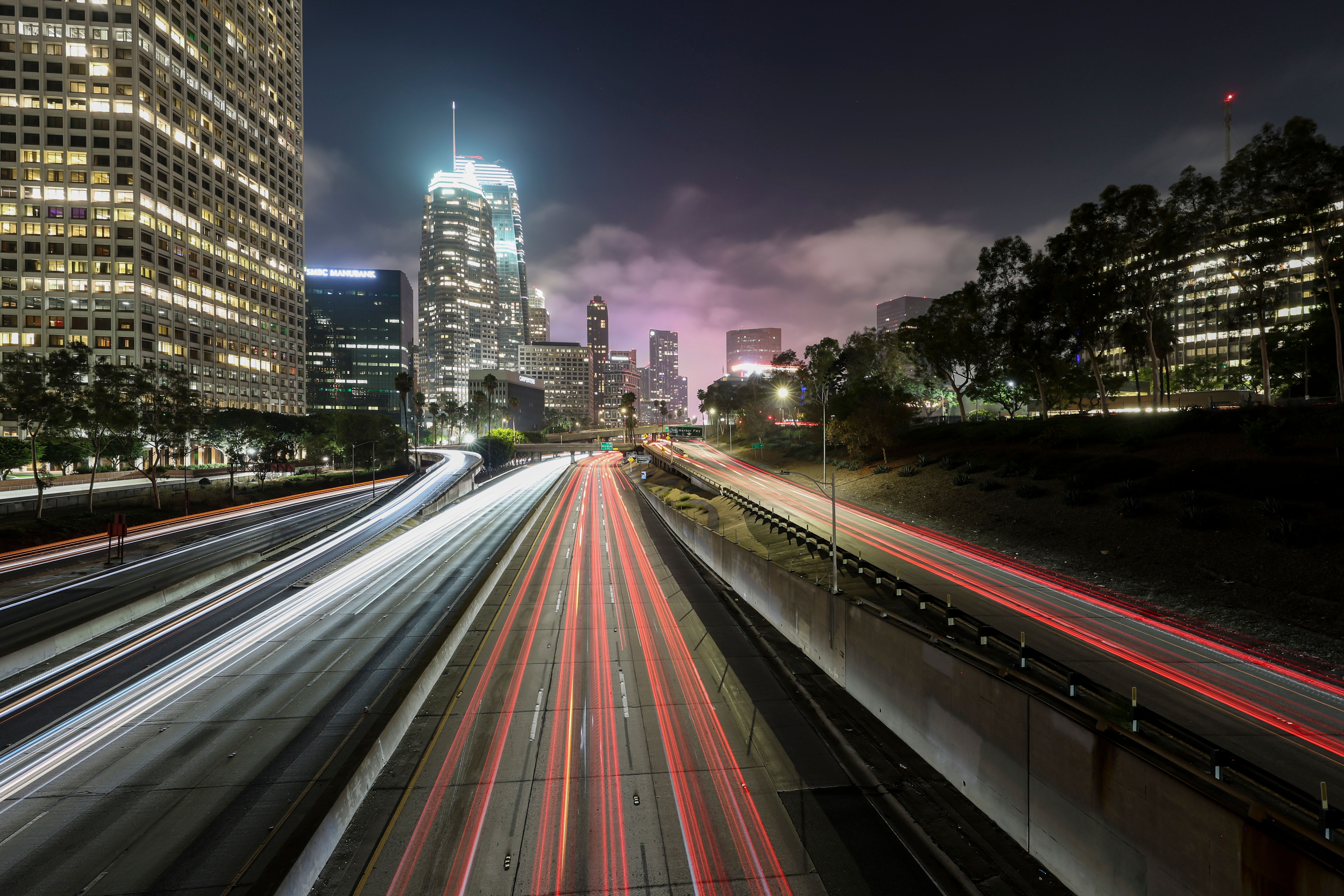Kostenlos Eine lebendige Langzeitbelichtung, die den geschäftigen Nachtverkehr von Los Angeles mit seinen beleuchteten Wolkenkratzern einfängt. Stock-Foto