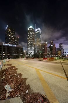 Captivating night view of downtown Los Angeles skyscrapers aglow with lights under cloudy skies.