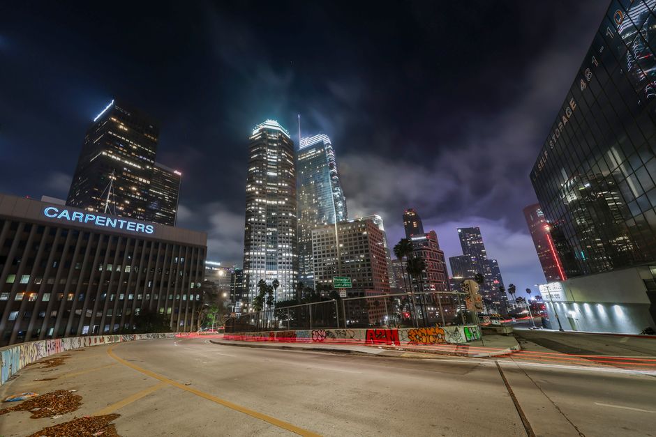 Vibrant night view of downtown Los Angeles with illuminated skyscrapers and light trails.