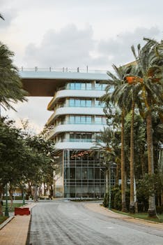 Photo by Dina Contemporary building with glass facade surrounded by lush palm trees, showcasing tropical modern architecture.