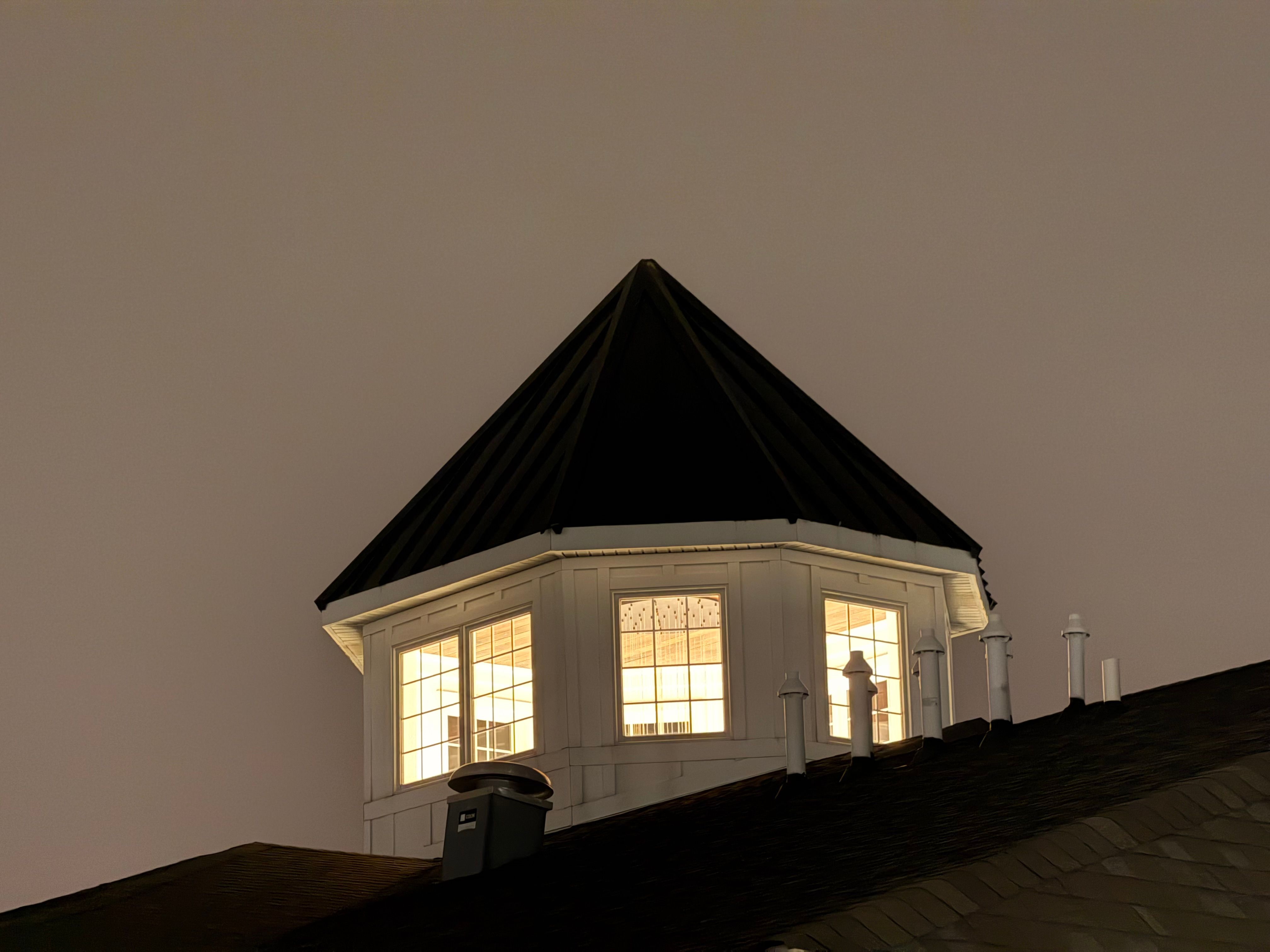 Illuminated rooftop tower with windows glowing against the night sky, creating a mysterious ambiance.