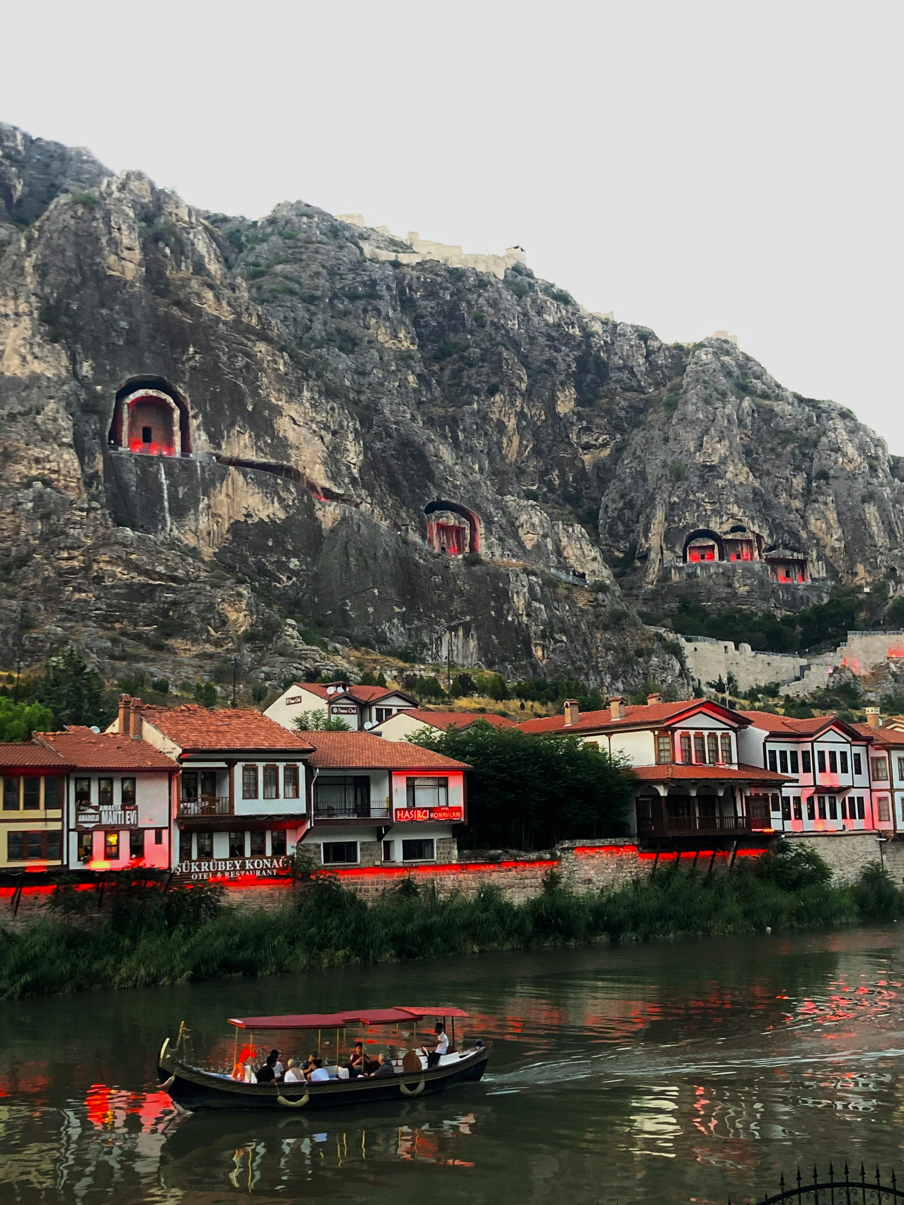 Free A scenic view of Ottoman houses and ancient rock tombs in Amasya, Turkey, with a boat on the river. Stock Photo
