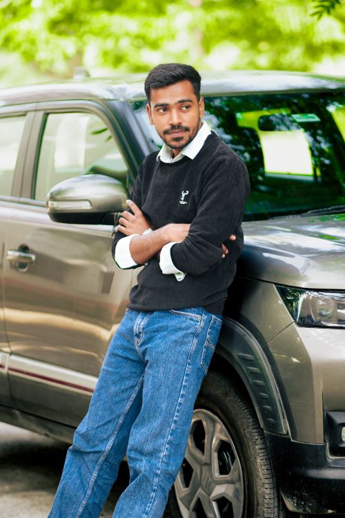 Free Man in casual clothing leaning on a car outdoors on a sunny day. Stock Photo