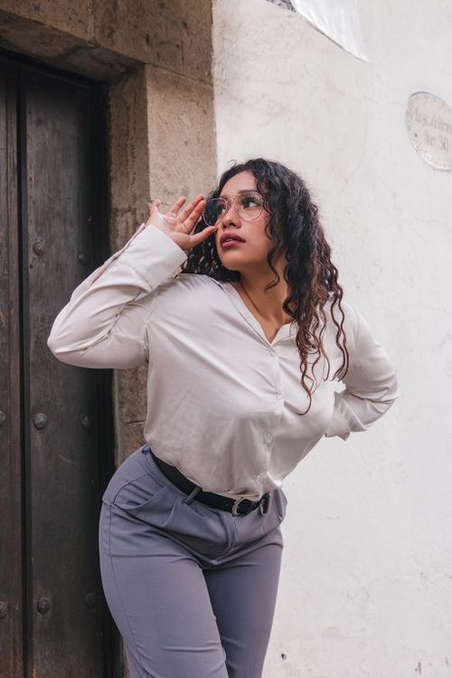Free Confident woman in glasses posing against a rustic door in an urban setting. Stock Photo
