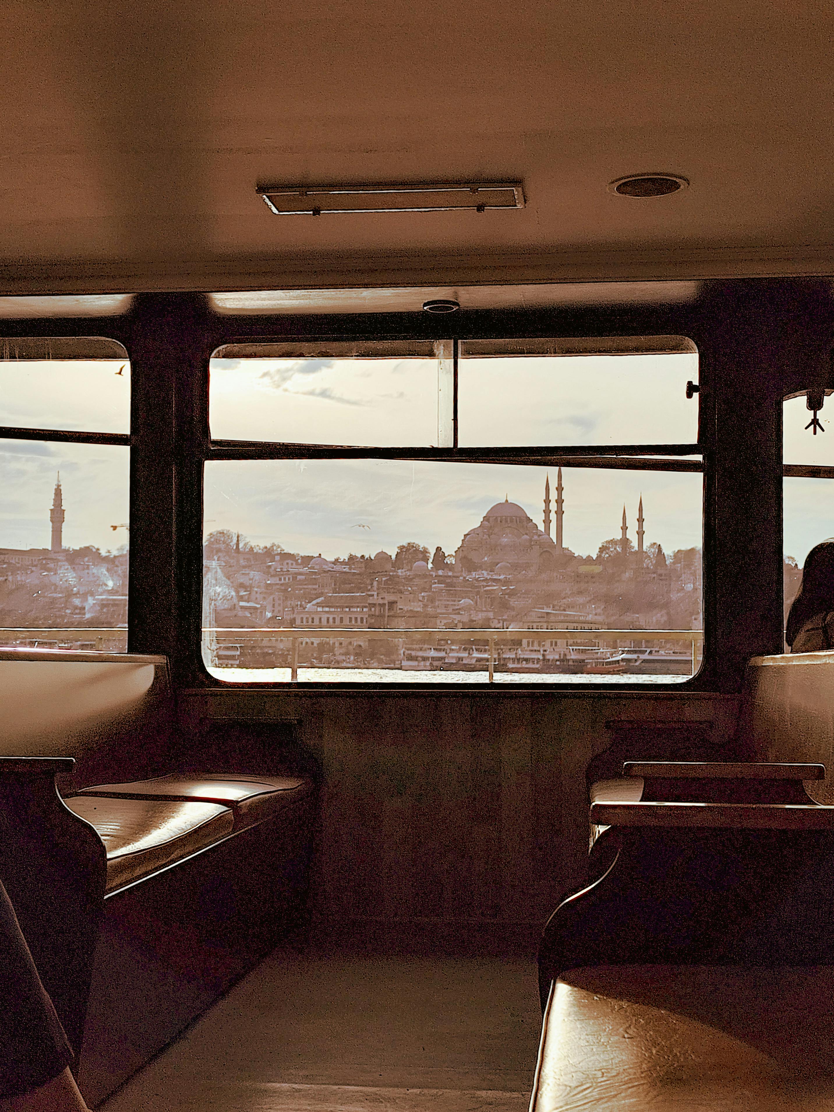 Scenic view of Istanbul skyline with mosques seen from a ferry window, capturing urban beauty.