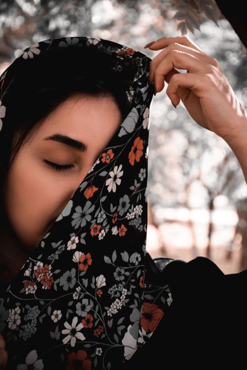 Free An adult with a patterned floral headscarf enjoys a peaceful moment outdoors. Stock Photo