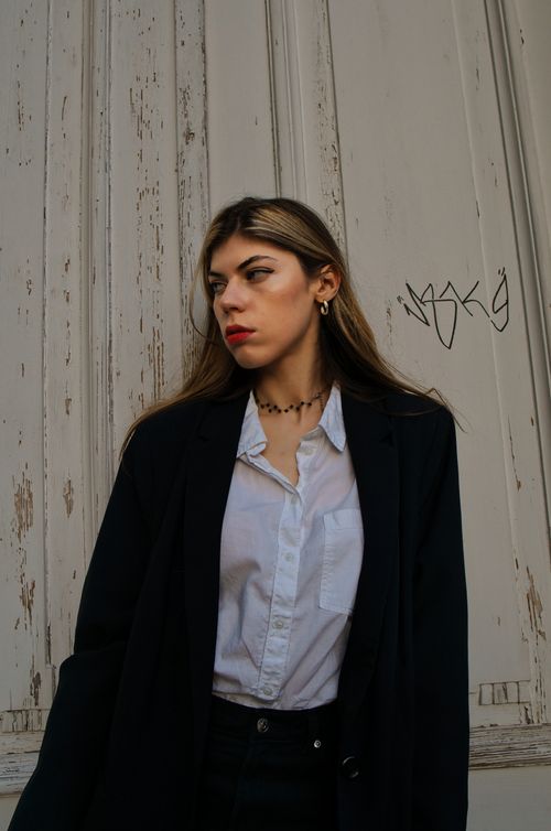 Free Elegant woman in business attire stands against rustic door in Berlin, exuding confidence. Stock Photo