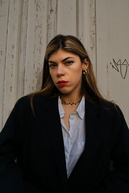Free Portrait of a stylish woman in Berlin exuding confidence against a rustic backdrop. Stock Photo